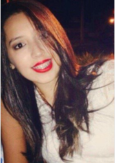Aluna Fernanda Karina da Silva Ribeiro. Mulher jovem de pele branca, cabelo liso com pontas onduladas de comprimento médio e cor castanho, está com a cabeça inclinada para esquerda, sorrindo e com fios de cabelo cobrindo parcialmente o olho direito. Olhos pretos. Usa uma camiseta de cor branca e batom vermelho. 