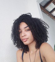 Aluna Jaiane Santana da Paz. Mulher jovem de pele preta, olhos castanhos e cabelo castanho, crespo, na altura dos ombros. Ela está com o rosto levemente virado para a esquerda, usa uma blusa azul de alças largas e um colar preto.